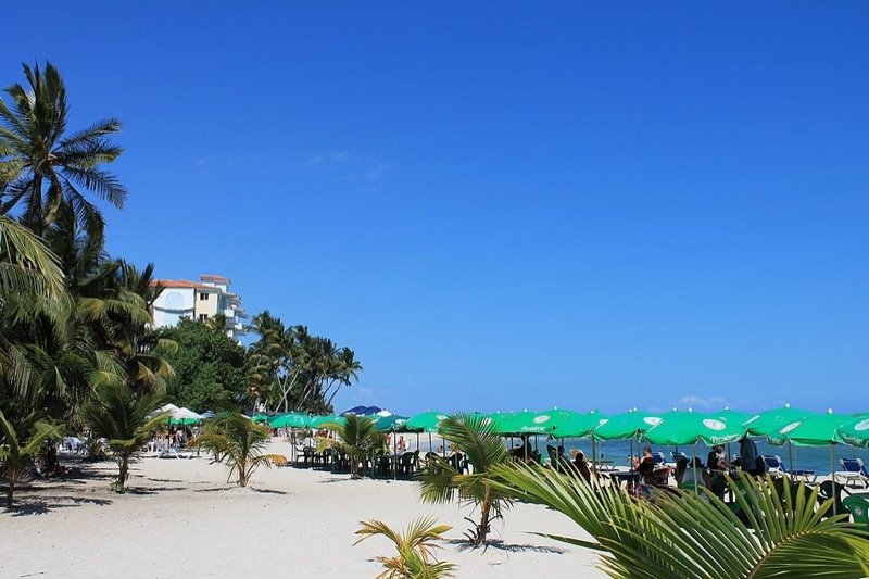 Playa de Juan Dolio con palmeras y sombrillas junto al mar